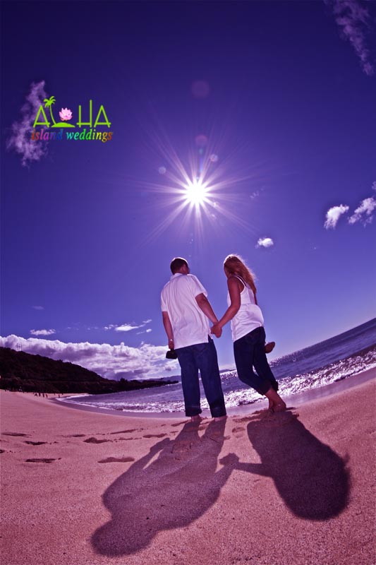 holding hand with the sun shinning up above with the waters ocean of Hawaii sparkling